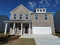 Charming two-story home with a grey brick exterior, covered porch, and attached two-car garage at 1640 Tide Mill Rd, Cumming, GA 30040