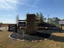 Community entrance sign for Klondike Reserve with stone pillar, black mulch, and young trees under a bright blue sky at 218 Seward St # 92, Conyers, GA 30094