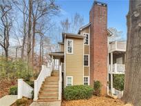 Inviting two-story home with a brick chimney, stairs, and balconies nestled among the trees at 2190 River Heights Se Ct, Marietta, GA 30067