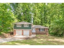 Split-level home with a brick facade and a two-car garage nestled among mature trees at 3661 Boring Rd, Decatur, GA 30034