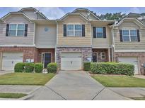 Charming townhome featuring a stone facade, one-car garage, and manicured landscaping at 2003 Burns View Ln # 2, Lawrenceville, GA 30044