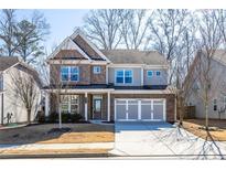 Beautiful two-story home featuring a brick and gray siding exterior with an attached three car garage at 333 Gardens Of Harmony Dr, Canton, GA 30115