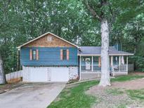 Charming two-story home with a welcoming front porch and well-maintained landscaping nestled between mature trees at 215 Little Brook Ln, Woodstock, GA 30188