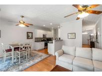 Bright living space featuring hardwood floors, an open kitchen, and white cabinets at 3626 Lantern Crest Cv, Scottdale, GA 30079