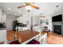 Bright living room and kitchen with hardwood floors, ceiling fans, fireplace and white cabinetry at 3626 Lantern Crest Cv, Scottdale, GA 30079