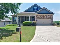 Charming home with a well-manicured lawn, covered porch, and a mix of brick and stone facade at 514 Creekshire Cir, Canton, GA 30115