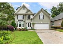 Charming home with a well-manicured lawn and a two-car garage, framed by mature trees and landscaping at 1450 Crescent Walk, Decatur, GA 30033