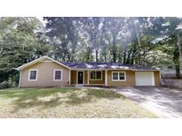 Charming single-story home with tan siding, mature trees, and a driveway at 5574 Oak Grove Dr, Acworth, GA 30102