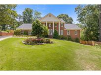 Charming two-story brick home with white columns, manicured lawn and colorful flowerbeds in a picturesque setting at 828 Jami Ct, Lawrenceville, GA 30046