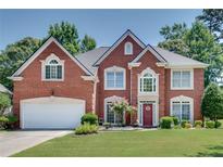 Traditional brick home with a two-car garage, lush lawn, and a charming, landscaped front yard at 3783 Wickford Ln, Peachtree Corners, GA 30096