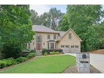 Charming two-story home with three-car garage, mature trees, and landscaped front yard at 10660 Dunoon Dr, Alpharetta, GA 30022