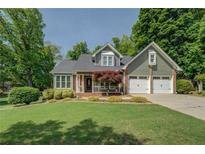 Charming home with a two-car garage, manicured lawn, beautiful landscaping, and mature trees providing shade at 1391 Sutters Dr, Lawrenceville, GA 30045