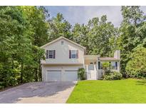 Charming split-level home featuring a two-car garage, and manicured lawn surrounded by mature trees at 441 Amy Blvd, Temple, GA 30179