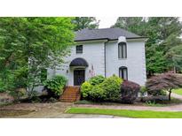 Charming white brick home featuring a covered entryway and beautifully landscaped front yard at 5025 Oak Bluff Ct, Atlanta, GA 30350