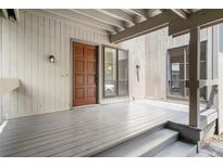 Inviting covered porch with paneled walls, warm brown front door, and gray painted wood flooring at 683 Highland Ct, Marietta, GA 30068