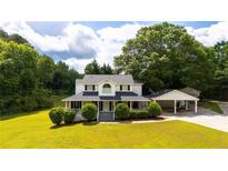 Charming two-story home featuring a welcoming front porch, a carport, and mature trees surrounding the property at 253 Pine Valley Dr, Powder Springs, GA 30127