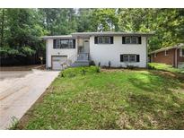 Charming two-story home with a white brick facade, black shutters, and well-maintained front yard at 3904 Bakers Ferry Sw Rd, Atlanta, GA 30331