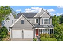 Charming two-story home featuring gray siding, a two-car garage, and a welcoming red front door at 3525 Elder Field Ln, Cumming, GA 30040