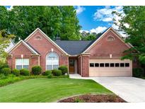 Charming brick home with manicured lawn, mature trees and attached two car garage, creating an inviting curb appeal at 4584 Brook Farms Dr, Duluth, GA 30096
