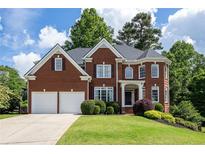 Charming two-story red brick home with well-manicured lawn, two-car garage and manicured shrubbery at 5370 Newport Bay Psge, Alpharetta, GA 30005