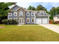 Charming two-story home featuring stone accents, a well-maintained lawn, and an attached two-car garage at 1583 Rogers Crossing Dr, Lithonia, GA 30058