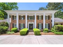 Stately brick home with white columns, black shutters, and manicured landscaping at 7590 Chaparral Dr, Atlanta, GA 30350