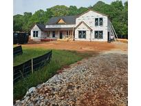 Exterior view of home under construction with new windows, black roof, and construction material in the yard at 95 Cambridge Dr, Covington, GA 30014
