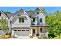 Charming two-story home with white siding, a well-manicured lawn, and an attached garage with metal awnings at 136 Beutell St, Norcross, GA 30071