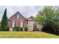 Traditional brick home featuring manicured lawn, stone accents and mature landscaping at 3784 The Great Dr, Atlanta, GA 30349