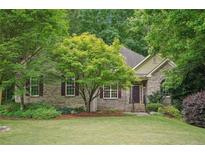 Charming brick home with lush landscaping, mature trees, and a well-manicured lawn creating a welcoming curb appeal at 2297 Herring Woods Way, Grayson, GA 30017