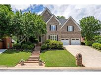 Charming two-story brick home featuring a well-manicured lawn, mature trees, and a two-car garage at 5589 Forkwood Nw Dr, Acworth, GA 30101