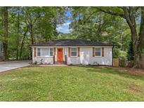 Charming home featuring an orange front door, complemented by white-painted brick and lush green landscaping at 1927 Willa Way, Decatur, GA 30032