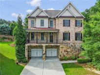 Charming two-story brick home with a stone foundation, a covered porch, and a two-car garage at 3394 Bryerstone Se Cir, Smyrna, GA 30080