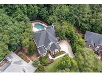 Stunning aerial view of home with pool, lush landscaping, and expansive driveway at 4567 Brigade Ne Ct, Roswell, GA 30075