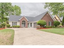 Charming single-story home with brick and siding exterior, a manicured lawn, and an expansive driveway at 4565 English Oaks Ln, Lilburn, GA 30047