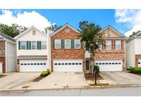Charming brick townhome featuring a one-car garage, green shutters, and well-maintained landscaping at 559 Woodland Park Ter, Lawrenceville, GA 30043
