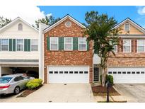 Two story brick townhome with a white garage door and manicured landscaping at 559 Woodland Park Ter, Lawrenceville, GA 30043