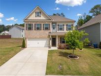 Charming two-story home featuring a brick and siding facade, a well-manicured lawn, and a two-car garage at 3360 Meadow Grass Dr, Dacula, GA 30019