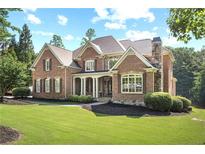 Beautiful brick home with a covered front porch, well-manicured lawn, and professional landscaping at 13037 Overlook Pass, Roswell, GA 30075