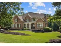 Stately brick home featuring manicured lawn, mature trees, and covered front entry at 13037 Overlook Pass, Roswell, GA 30075