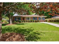 Charming single-story brick home with lush green lawn, mature trees, and blue shutters at 3060 Wilson Rd, Decatur, GA 30033