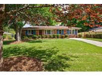 Charming brick home with a well-manicured lawn, blue shutters, and mature trees for shade at 3060 Wilson Rd, Decatur, GA 30033