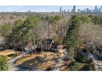 An aerial view shows a brick home situated on a lot with mature trees and views of the Atlanta skyline at 725 Glengary Ne Way, Atlanta, GA 30342