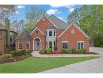 Charming brick home featuring lush landscaping, a well-manicured lawn, and a welcoming entrance at 1025 Saint Marks Walk, Suwanee, GA 30024