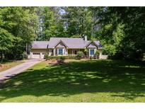 Charming ranch-style home with a well-manicured lawn and a driveway leading to a two-car garage, nestled among lush trees at 261 Township Dr, Hiram, GA 30141