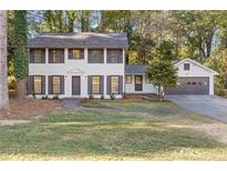 Charming two-story home features a well-manicured lawn, fresh paint, shutters, and an attached two-car garage at 4045 White Oak Sw Ln, Lilburn, GA 30047