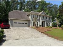 Charming two-story home featuring a spacious driveway and a manicured lawn, surrounded by lush trees at 1368 Christiana Dr, Lawrenceville, GA 30043