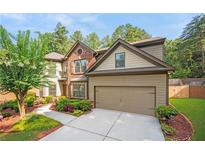 Charming two-story home featuring brick and tan siding, with a well-manicured lawn and two car garage at 1736 Dylan Pl, Lawrenceville, GA 30043