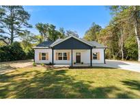 Charming one-story home boasts a well-manicured lawn, complemented by tasteful wooden shutters and a modern black accent wall at 389 Campground School Rd, Dallas, GA 30157