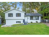 Charming split-level home with white exterior, black shutters, and well-manicured lawn at 6864 Maddox Rd, Morrow, GA 30260